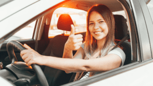happy vehicle owner sitting in car giving thumbs up